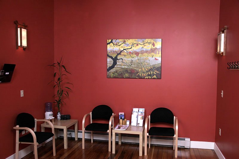 The clinic's warm waiting room with wooden chairs and a bamboo plant