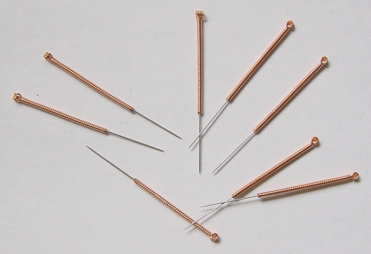 Several fine acupuncture needles laid out on a white surface